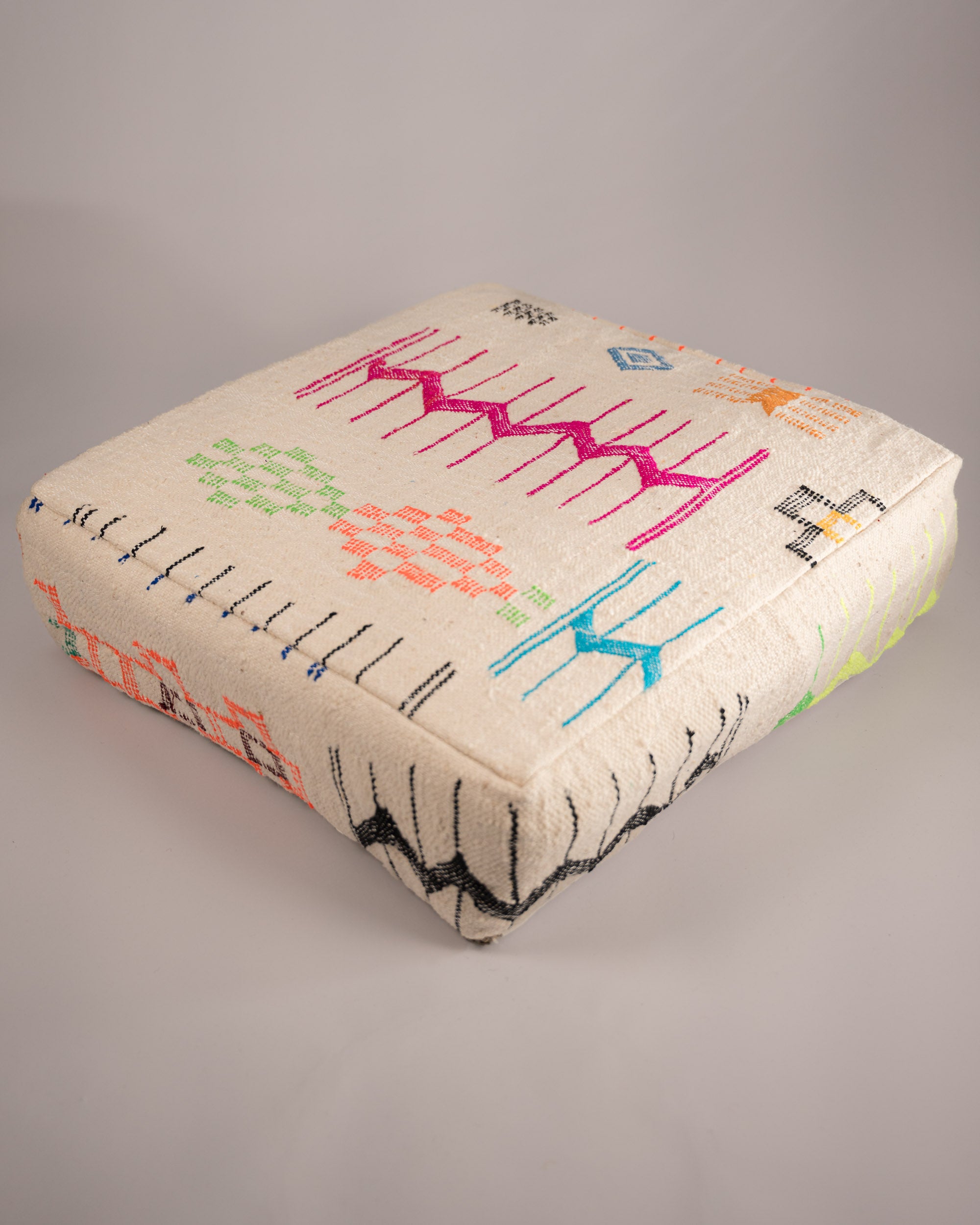 Handgemachter Boho-Pouf aus Schurwolle weiß pink bunt gemustert