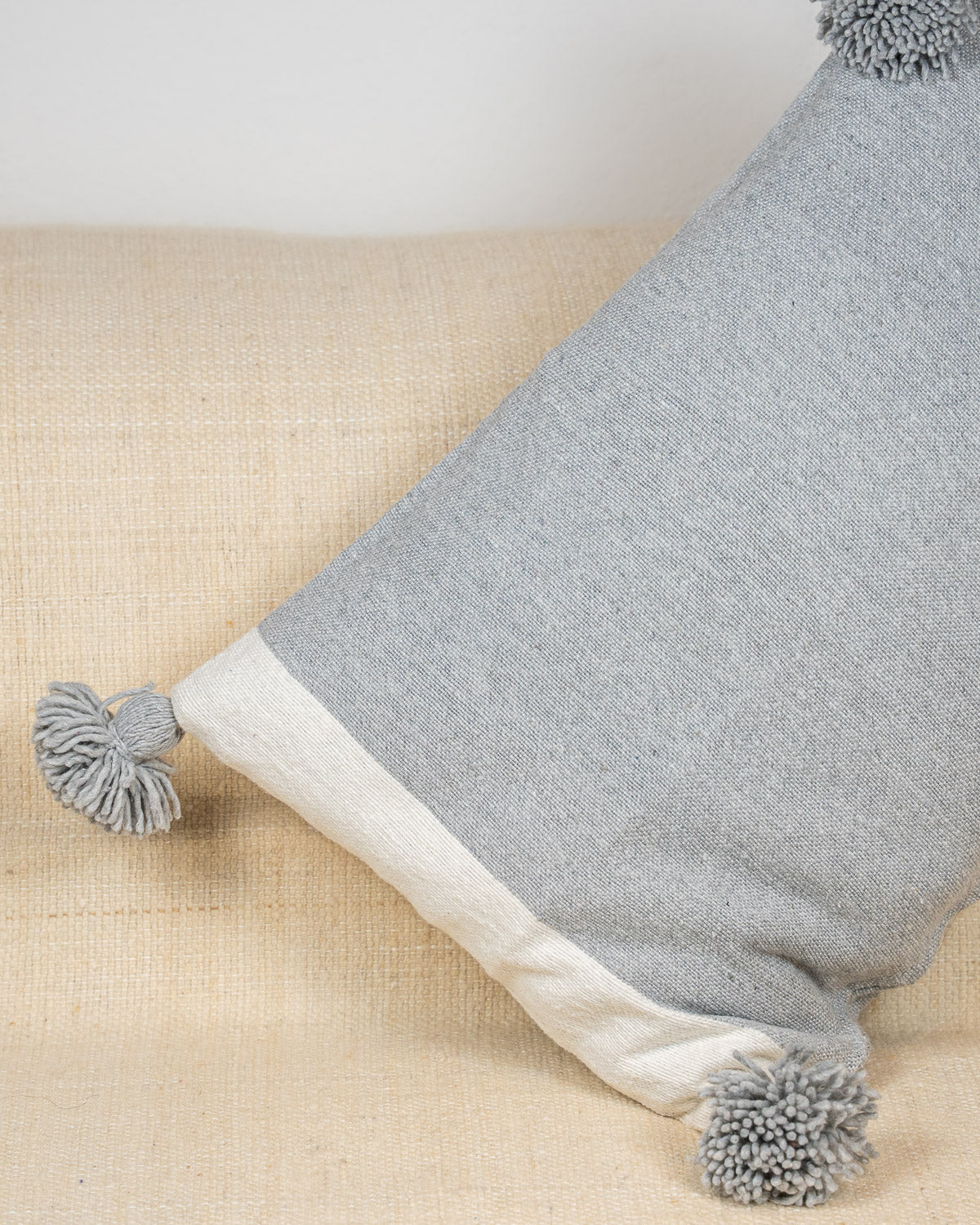 Berber Kissen fürs Sofa grau mit Pompons – Handgewebte Deko Kissenhülle grau Boho Style bei MOGADOR