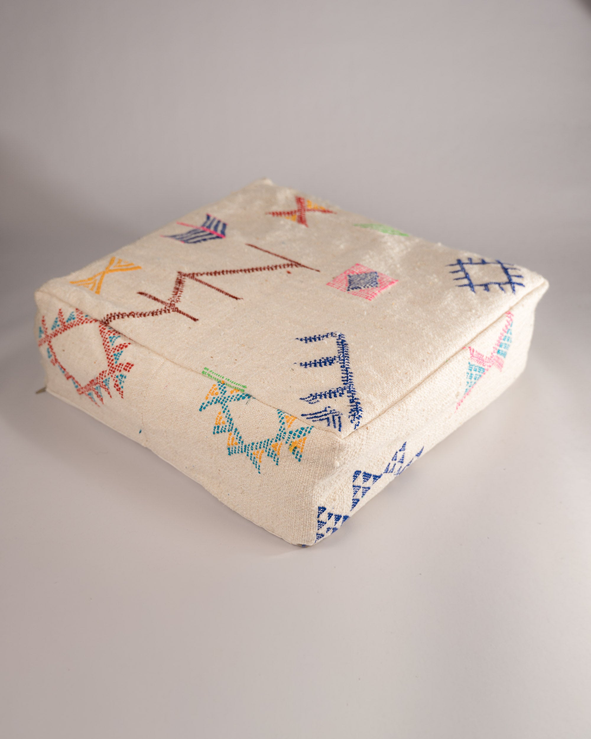 Handgemachter Boho-Pouf aus Schurwolle weiß bunt gemustert